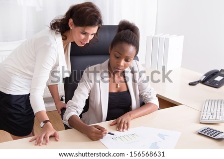African American businesswoman showing chart to her Caucasian colleague.