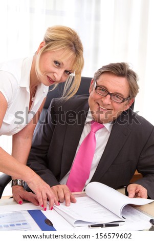Caucasian man and woman looking at camera in office.