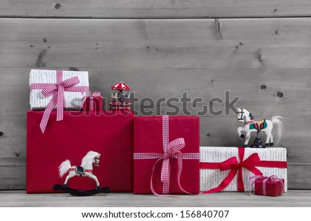 Red Christmas presents and gift boxes with rocking horse on grey wooden background