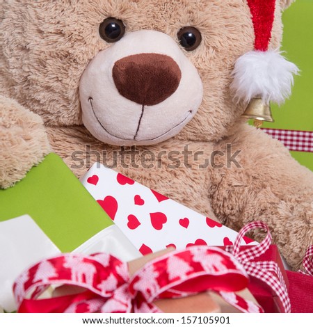 Close up of smiley teddy bear with gift boxes and christmas hat