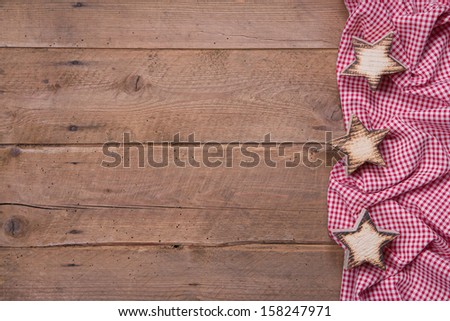 Wooden background with stars and a red checkered frame for Christmas or for a greeting card