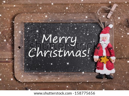 Chalk board with Merry Christmas message , santa and snowflakes on wooden background for a greeting card