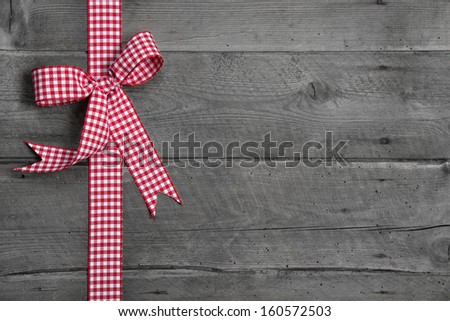 Grey wooden background with red and white checkered bow as border Grey wooden background with red and white checkered bow as border