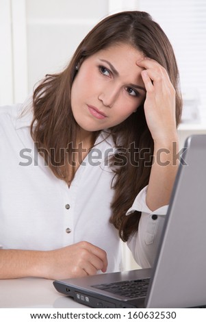 Headache: businesswoman scratching forehead with laptop