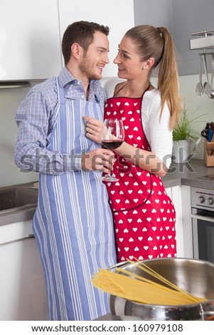 Couple in love cooking together in the kitchen and have fun - drinking red wine