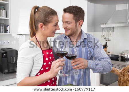 Couple celebrate love - cooking together in the kitchen and have fun - drinking red wine