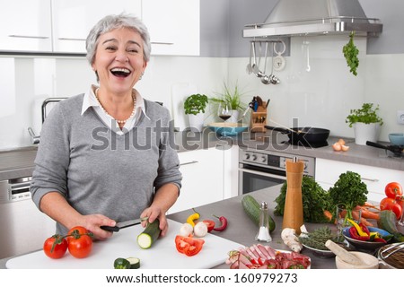 Senior or older woman with grey hair cooking in kitchen - vegetables