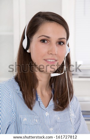 Pretty businesswoman in white sitting at helpdesk and laptop with headset