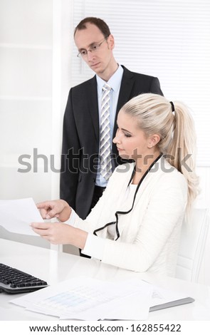 Successful businessman with suit and tie talking with his blond beautiful secretary