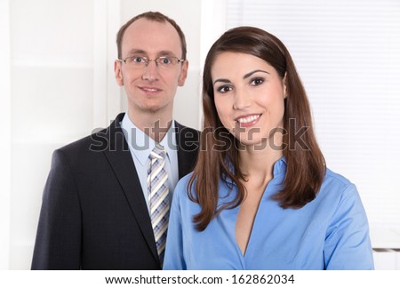 Portrait of a successful business team - he in suit and tie and she smiling in a blue blouse - teamwork