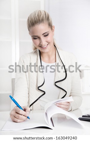 Happy young smiling woman working in a bank or insurance satisfied with his job sign a business letter.