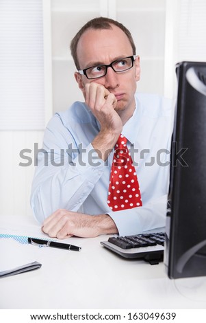 Young businessman with glasses and bald sitting in his office in a blue shirt with red tie - thinking about his future.