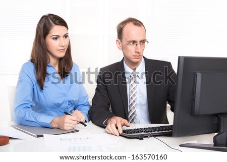 Two business people sitting at desk - concept for teamwork.  Two business people sitting at desk. Man and woman - boss and secretary or colleagues in an office.