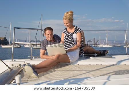 Two business people working with laptop on a sailing boat - sailing trip.