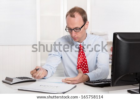 Quizzically engineer or specialist in shirt and tie sitting at desk