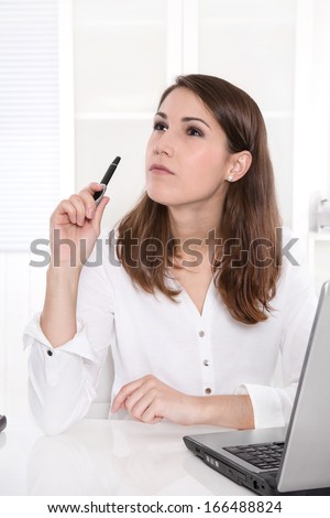 Idea: business woman thinking with pen in hand at Office.