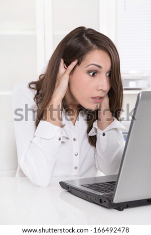 Shocked and stressed business woman at desk with her computer - problems at work.