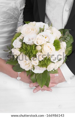 Wedding: Bride and groom holding hands with bridal bouquet