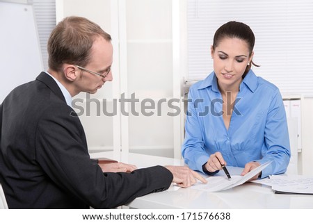 Two business people talking together at desk - adviser and customer