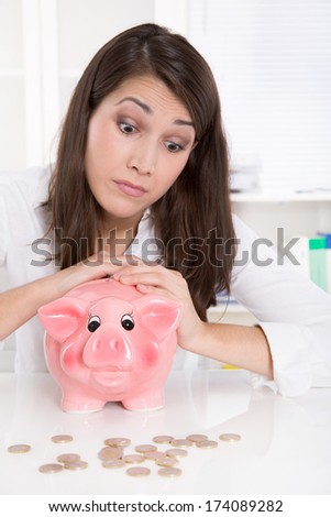 Woman is counting her money - sitting sad at desk.