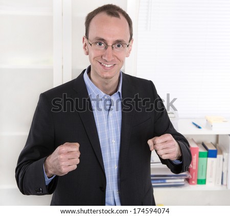 Successful businessman with suit and closed fists smiling at office - power