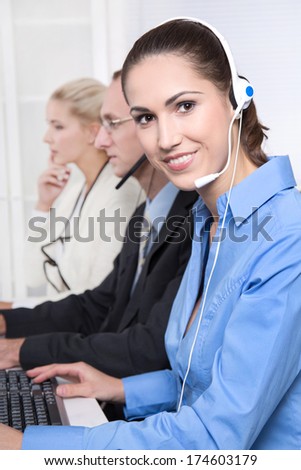 Telesales or helpdesk team - helpful woman with headset smiling at camera - workers at call center