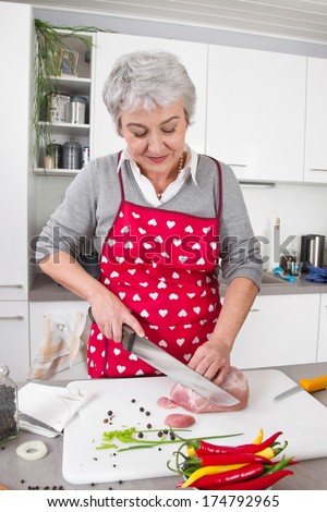 Senior or older woman with grey hair cooking in kitchen.