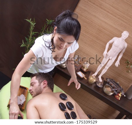 Female thai masseur making hot stone in a spa center with a man.