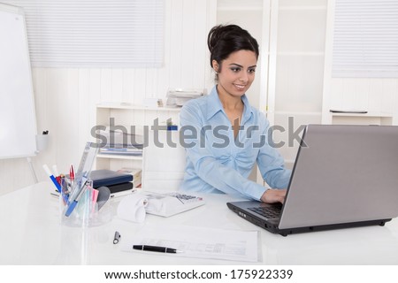 Indian woman sitting happy in her office.