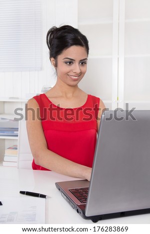 Beautiful asian secretary in red working with laptop at office.