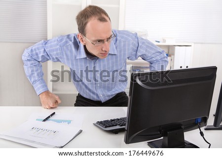 Computer crash: shocked manager in blue shirt in front of his computer at office.
