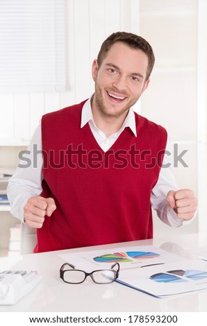 Happy bookkeeper with fists at desk at office.