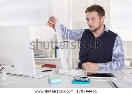 Young attractive accountant working with calculating machine at desk..