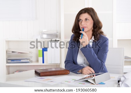 Unhappy older pensive business woman sitting at desk.