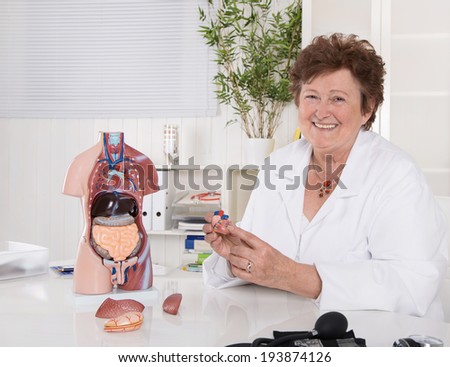Portrait of happy older senior doctor explaining the human body.