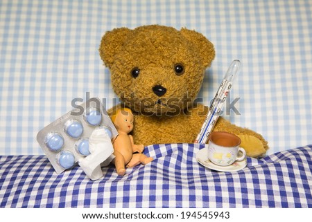 Sick teddy bear lying with medicaments in the bed. Concept for ill children.