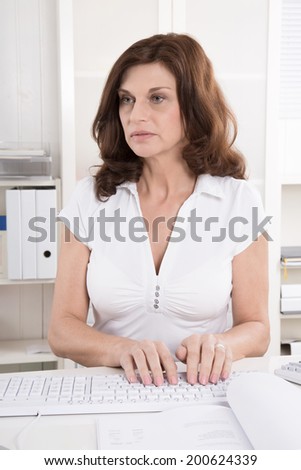 Portrait: Attractive middle aged woman writing on computer.
