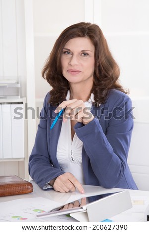 Portrait: Successful middle-aged attractive woman sitting in the office.