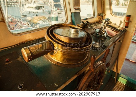Old ancient steering wheel of copper in the cockpit of an old antique ship.