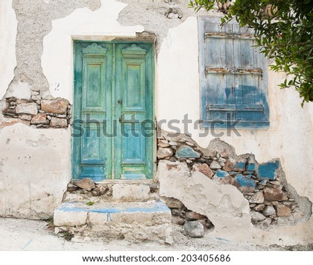 Old wooden door of a shabby demaged house facade or front in blue, green and turquoise.
