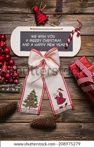Xmas card: We wish you a merry christmas and a happy new year. Red and white decoration on wooden background.