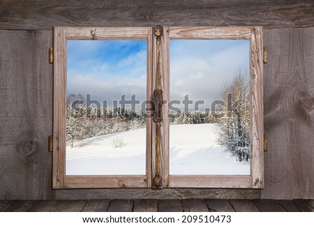 Snowy winter landscape. View out of an old rustic wooden window.