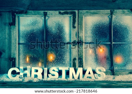 Atmospheric old christmas window with red candles and text.