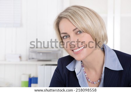 Attractive middle aged woman in business outfit sitting in her office.