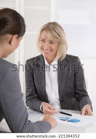 Two business woman sitting at desk: customer and adviser talking together.