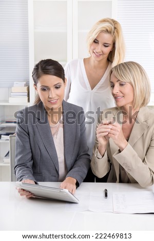 Team: Successful business team of woman in the office talking together looking at tablet computer.