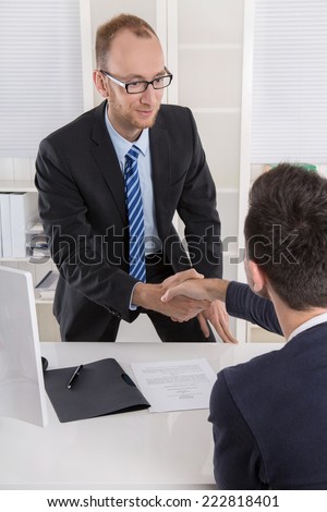 Smiling manager says hello to a candidate in a job interview with handshake.