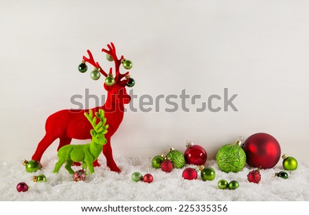 Red and green christmas decoration with snow: Reindeer with balls on wooden white background.