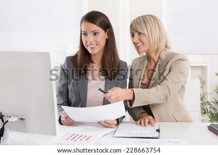 Two attractive business woman sitting together in a team in the office.