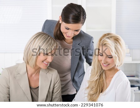 Successful team of well educated businesswoman sitting at desk wearing business outfit.